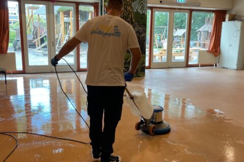 Koen de Poetskampioen reinigt een linoleum vloer met een machine.